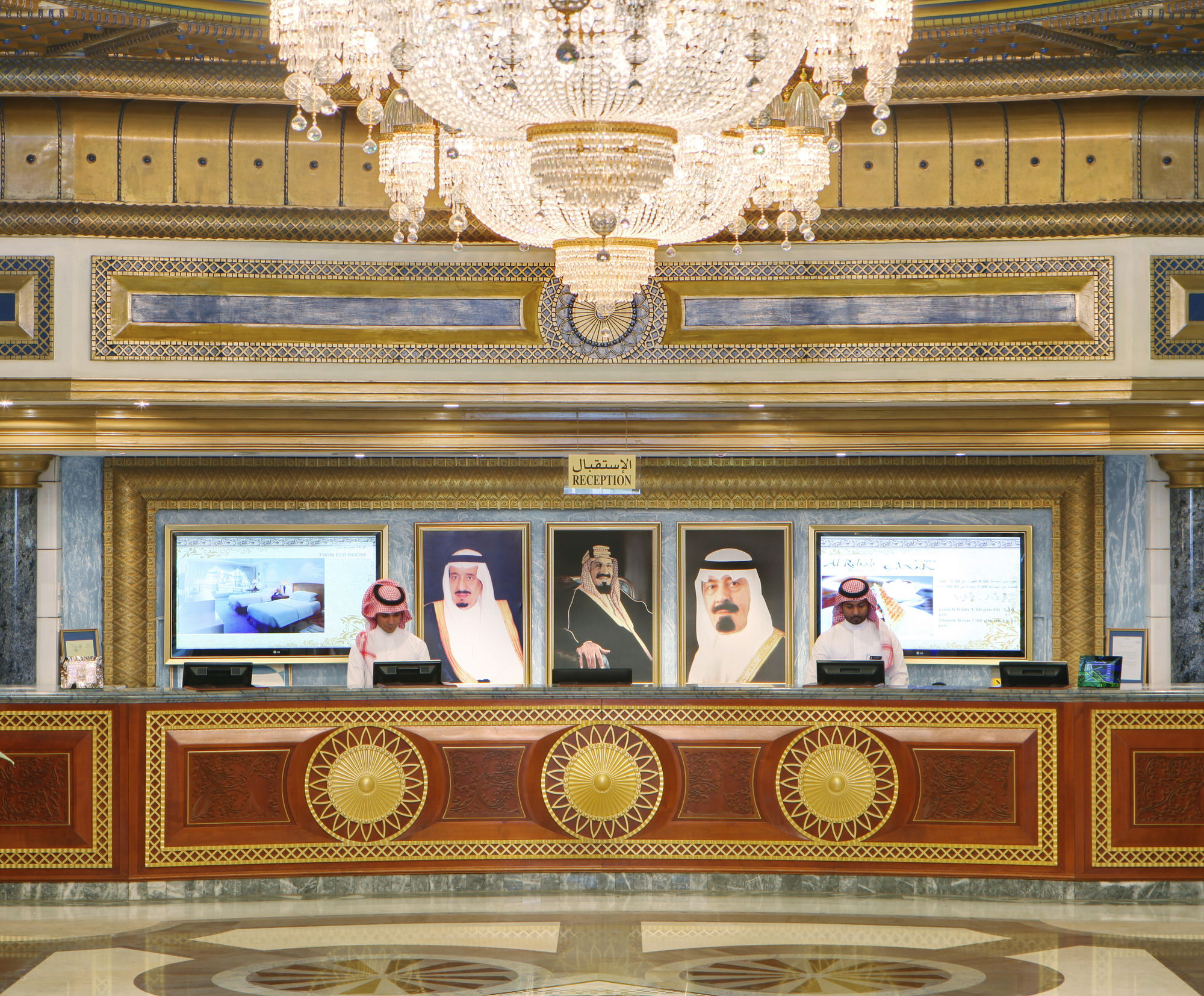 Hotel Dar Al Tawhid Intercontinental Makkah By Ihg Mekka Exterior foto The photo shows a luxurious reception area, likely in a hotel or official building. The decor features ornate details, including a large chandelier hanging from the ceiling. Behind the reception desk, there are several framed portraits, probably of n